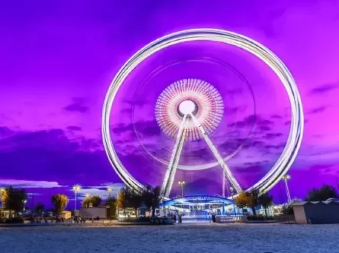 Ruota panoramica luminosa sotto un cielo viola intenso, atmosfera magica e surreale.