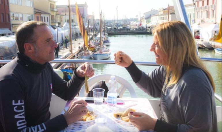 Deux personnes mangent ensemble près d'un canal avec des bateaux.