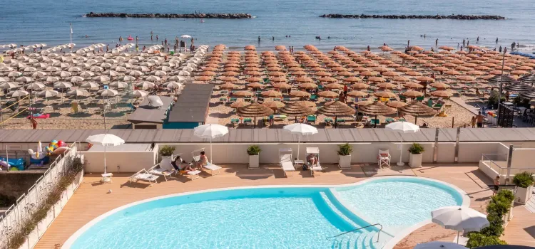 Spiaggia affollata, ombrelloni colorati e piscina rinfrescante, atmosfera estiva vivace.