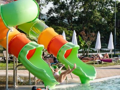 Bambini si divertono sugli scivoli d'acqua in piscina.