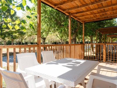 Terrazza in legno con tavolo bianco, immersa nel verde.