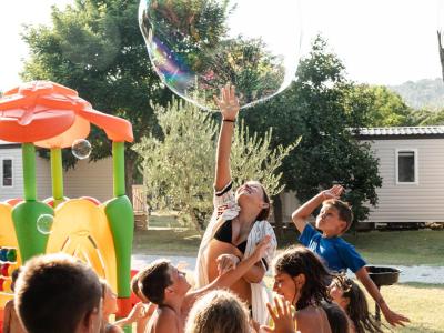 Bambini felici giocano con bolle giganti in un parco soleggiato.