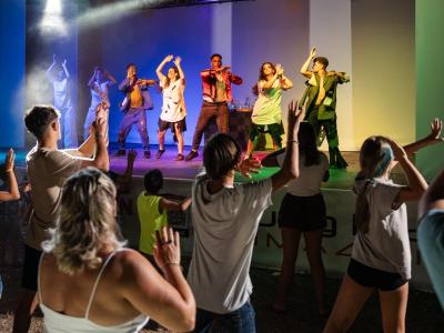 Spettacolo di danza energico, pubblico coinvolto e luci colorate sul palco.