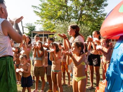 Bambini giocano felici con la schiuma sotto il sole estivo.