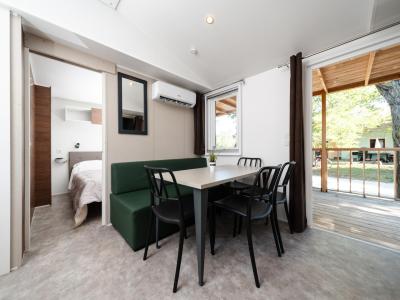 Interno accogliente, tavolo moderno, luce naturale, vista su veranda verde.