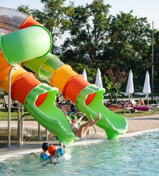 Bambini si divertono sugli scivoli d'acqua in piscina.