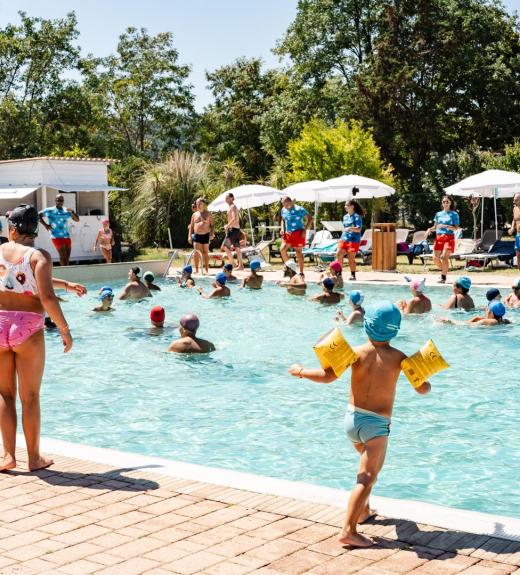Bambini giocano felici in piscina sotto il sole estivo.