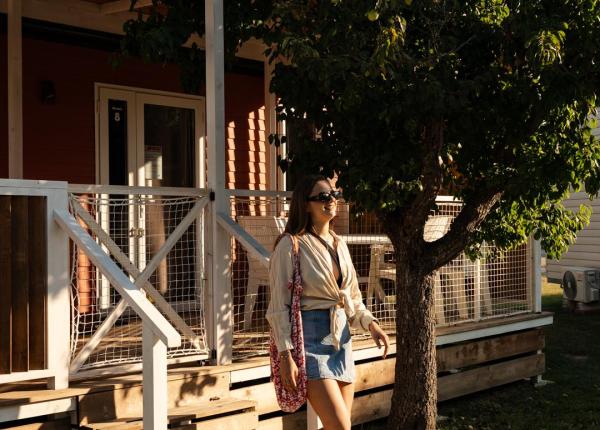 Donna cammina al sole vicino a una casa di legno.