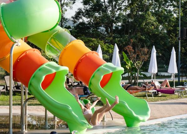 Bambini si divertono sugli scivoli d'acqua in piscina.