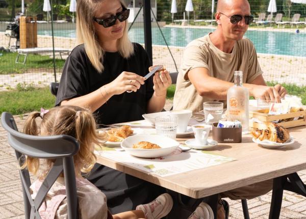 Famiglia fa colazione all'aperto vicino alla piscina.