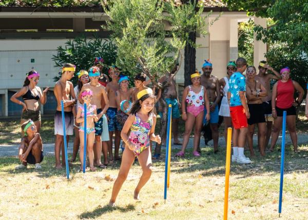 Bambini giocano all'aperto con ostacoli colorati.