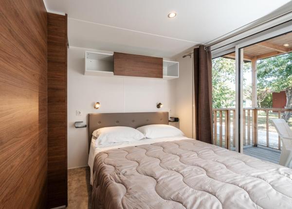 Gemütliches Zimmer mit Doppelbett, sanftem Licht und Blick auf die Natur.
