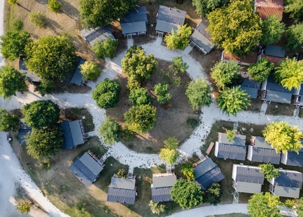 Vista aerea di casette tra alberi, creando un'atmosfera di tranquillità e natura.