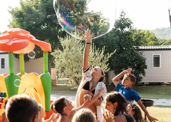 Bambini felici giocano con bolle giganti in un parco soleggiato.