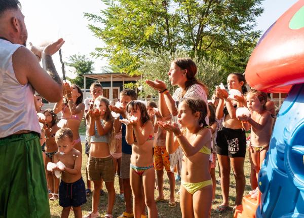 Bambini giocano felici con la schiuma sotto il sole estivo.