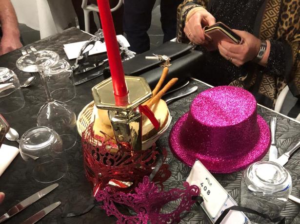 Table avec décorations, chapeau pailleté et bougie rouge.