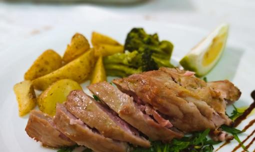 Meat dish with potatoes, broccoli, and lemon, garnished with balsamic glaze.