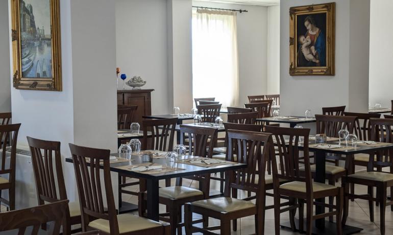 Ristorante elegante con quadri alle pareti e tavoli apparecchiati.