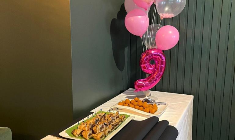 Party table with pink balloons and assorted food.