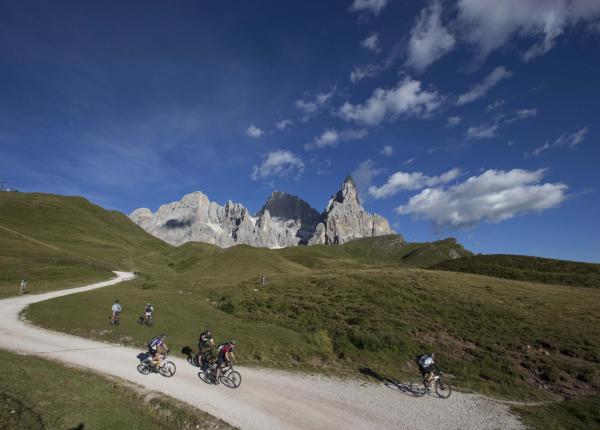 Cyclists on a mountain trail with a view of the Dolomites.